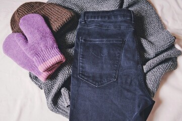 Winter trendy fashion outfit. Brown hat, gray scarf, purple gloves and dark skinny jeans. Warm clothes for cold weather