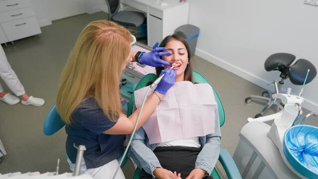 Professional Woman Dentist Examines a Female Patient with a Special Tool and Prescribes Treatment in a Modern Dental Clinic. Oral Hygiene. Concept of Healthcare and Medicine. Slow Motion. 
