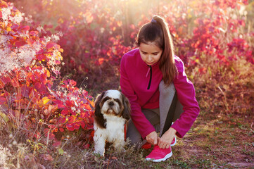 Sporty woman tying shoelaces after jogging with dog