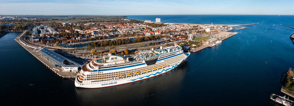 Rostock, Warnemuende, Germany - October 2022, The cruise ship "AIDA diva" of AIDA Cruises has moored at the Cruise Ship Terminal - the city of Warnemuende with landmarks in the background - panoramic