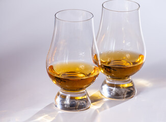 Tulip-shaped tasting glasses with dram of Scotch single malt or blended whisky on white background