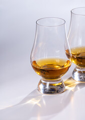 Tulip-shaped tasting glasses with dram of Scotch single malt or blended whisky on white background