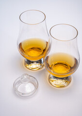 Tulip-shaped tasting glass with dram of Scotch single malt or blended whisky on white background