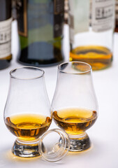 Tasting of whiskey, tulip-shaped tasting glasses with dram of Scotch single malt or blended whisky on white table
