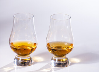 Tulip-shaped tasting glasses with dram of Scotch single malt or blended whisky on white background