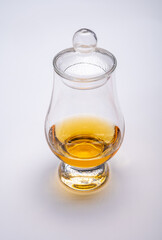 Tulip-shaped tasting glass with dram of Scotch single malt or blended whisky on white background