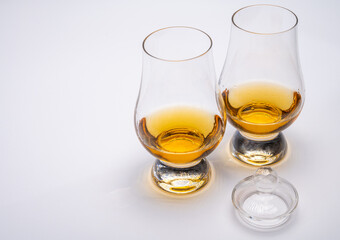Tulip-shaped tasting glass with dram of Scotch single malt or blended whisky on white background