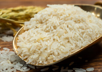 Organic white uncooked rice and dried basmati rice plant onwooden table