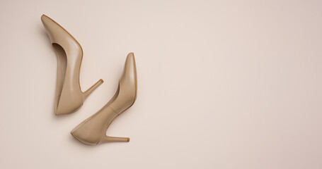 Leather beige high heel shoes on a beige background, top view - obrazy, fototapety, plakaty