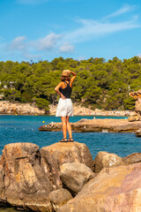 A young woman on the rocks on vacation in Ibiza at Salada y Saladeta beach. Balearic