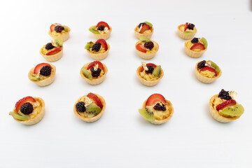 rows of delicious cupcakes with cream and fruits as decoration, details in studio, gourmet food with white background, pastries