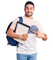 Young handsome man wearing student backpack and notebook smiling happy pointing with hand and finger