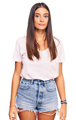 Young hispanic woman wearing casual white tshirt relaxed with serious expression on face. simple and natural looking at the camera.