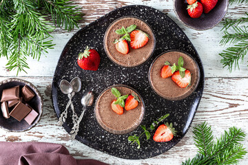 Homemade delicious chocolate mousse or panna cotta with berries on a white stone or wooden background. Festive dessert.