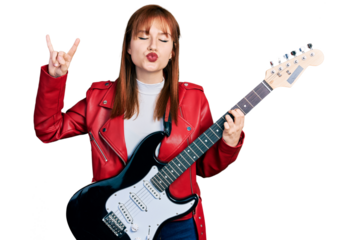 Redhead young woman playing electric guitar doing rock gesture looking at the camera blowing a kiss being lovely and sexy. love expression.
