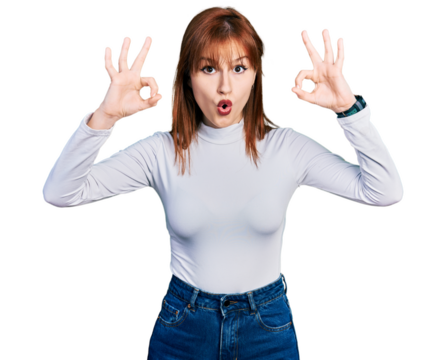 Redhead young woman wearing casual turtleneck sweater looking surprised and shocked doing ok approval symbol with fingers. crazy expression
