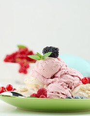Vanilla and raspberry ice cream scoops on a round green plate