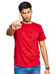 Young handsome man wearing casual red tshirt pointing with finger up and angry expression, showing no gesture