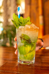 Hand of a young girl taking an ideal Mojito cocktail to cool off on summer vacations