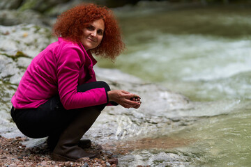 Woman collecting pebbles on river bank