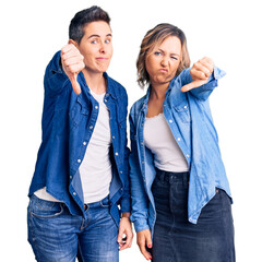 Couple of women wearing casual clothes looking unhappy and angry showing rejection and negative with thumbs down gesture. bad expression.