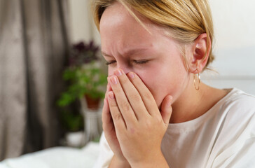 The sick girl coughs heavily, covering her mouth with her hands.