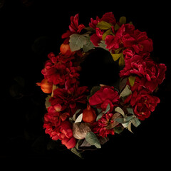 Highlighted red and green holiday welcoming wreath on a solid black background
