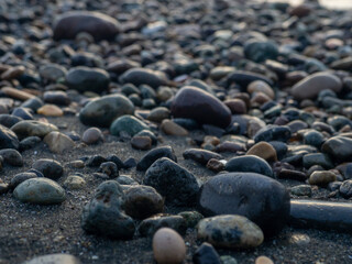 Pebbles on the seashore close-up. Rocky beach. Stones close-up with bokeh. Gray natural background.   Waves and wet pebbles