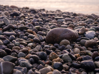 Pebbles on the seashore close-up. Rocky beach. Stones close-up with bokeh. Gray natural background. Autumn on the seashore.