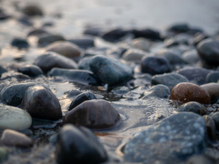 Fototapeta na wymiar Pebbles on the seashore close-up. Rocky beach. Stones close-up with bokeh. Gray natural background. The concept of rest on the seashore. Autumn on the seashore. Waves and wet pebbles
