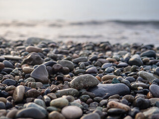 Pebbles on the seashore close-up. Rocky beach. Stones close-up with bokeh. Gray natural background. Autumn on the seashore.