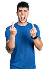 Young hispanic man wearing casual t shirt showing middle finger doing fuck you bad expression, provocation and rude attitude. screaming excited