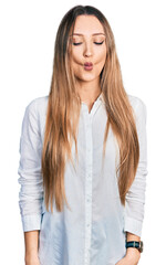 Beautiful caucasian woman wearing casual white shirt making fish face with lips, crazy and comical gesture. funny expression.