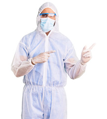 Fototapeta premium Young hispanic man wearing doctor protection coronavirus uniform and medical mask smiling and looking at the camera pointing with two hands and fingers to the side.