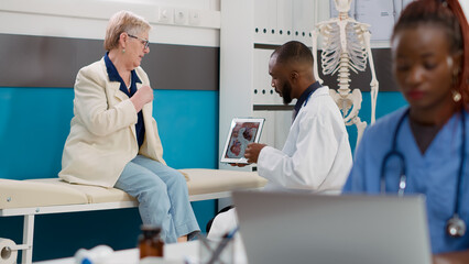 Obraz premium Cardiology medic showing cardiogram diagnosis on digital tablet to sick woman with cardiac disease. Looking at cardiovascular ecg and heart organ on display to find healthcare treatment.