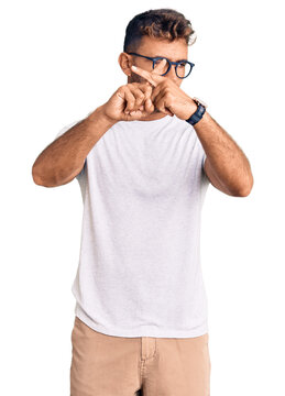 Young hispanic man wearing casual clothes and glasses rejection expression crossing fingers doing negative sign