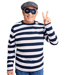 Senior handsome man wearing burglar mask and t-shirt smiling with happy face winking at the camera...