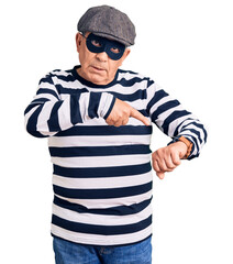 Senior handsome man wearing burglar mask and t-shirt in hurry pointing to watch time, impatience, upset and angry for deadline delay
