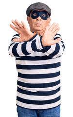 Senior handsome man wearing burglar mask and t-shirt rejection expression crossing arms doing negative sign, angry face