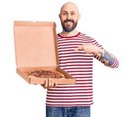 Young handsome man holding delivery pizza box smiling happy pointing with hand and finger
