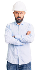 Young handsome man wearing architect hardhat skeptic and nervous, disapproving expression on face with crossed arms. negative person.