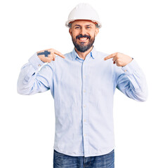 Young handsome man wearing architect hardhat looking confident with smile on face, pointing oneself with fingers proud and happy.