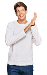 Handsome caucasian man wearing casual white sweater clapping and applauding happy and joyful, smiling proud hands together