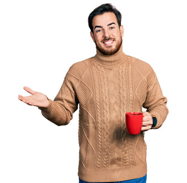 Young hispanic man holding coffee celebrating achievement with happy smile and winner expression with raised hand