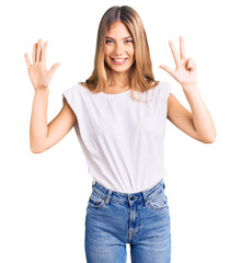 Fototapeta na wymiar Beautiful caucasian woman with blonde hair wearing casual white tshirt showing and pointing up with fingers number eight while smiling confident and happy.