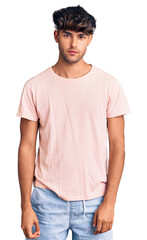 Young hispanic man wearing casual clothes with serious expression on face. simple and natural looking at the camera.