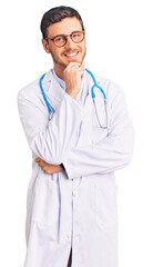Fototapeta premium Handsome young man with bear wearing doctor uniform looking confident at the camera with smile with crossed arms and hand raised on chin. thinking positive.