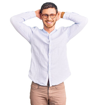 Handsome young man with bear wearing elegant business shirt and glasses relaxing and stretching, arms and hands behind head and neck smiling happy