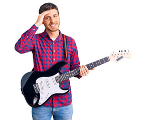 Handsome young man with bear playing electric guitar stressed and frustrated with hand on head, surprised and angry face