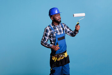 House painter making interior renovation, painting walls with roller. Construction worker wearing...